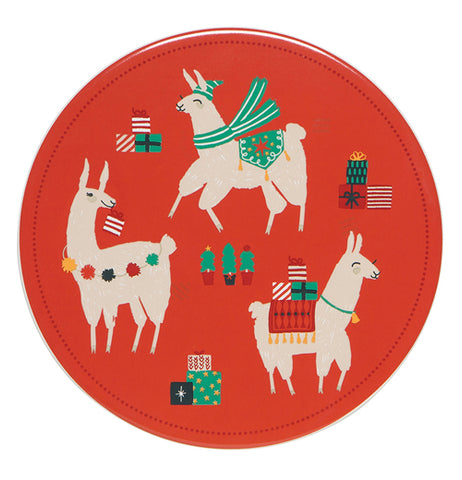 This red trivet features a design of three white llamas wearing different Christmas attire. The first one is wearing a green scarf, a green hat, and a green carpet on its bag. The second is shown with a red carpet on its back with wrapped up Christmas presents and wearing a bell around its neck. The third one has a string of puffballs around its neck and is holding a red and white stocking. In the middle of the trivet are some miniature Christmas trees.