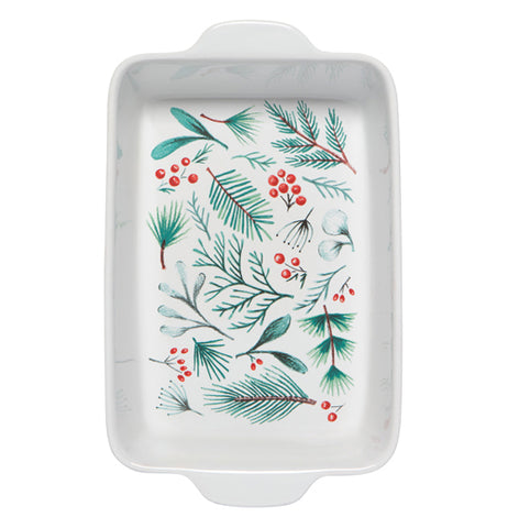 This red baking dish has a white interior decorated with red berries and green pine needles and leaves.