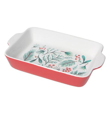 This red baking dish has a white interior decorated with red berries and green pine needles and leaves.