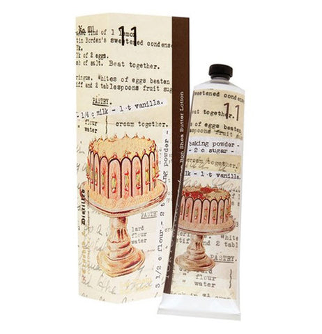 This vintage looking Shea butter lotion has a cake illustrated on it. The lotion is placed next to it's box. The cake is sitting on a old modern day table.