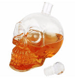A bright orange alcoholic beverage is shown inside the human skull-shaped glass container, which has its lid off.