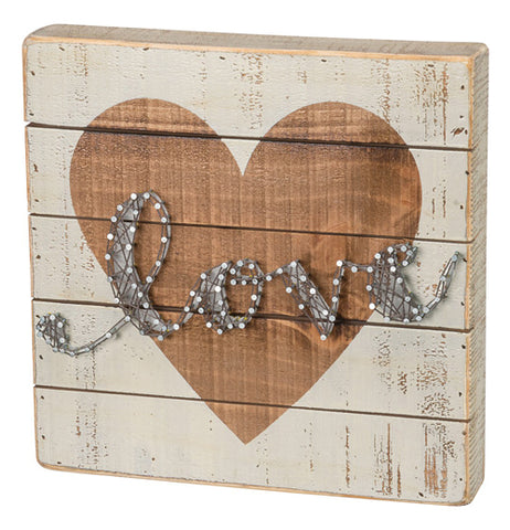 White wooden shiplap box sign with a gold heart in the middle and the word "Love" written in string art. 