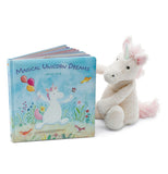 Magical Unicorn Dreams book slightly open standing up next to a white and pink stuffed unicorn.