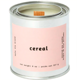 A gray tin candle-shaped can with a pastel pink label. The label says "Mala the brand--cereal--Net weight 8 oz. -- scented soy candle." There is also French text, but this alt text writer is woefully monolingual.