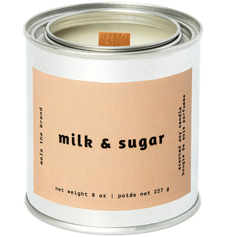 A gray tin candle-shaped can with a pastel brown label. The label says "Mala the brand--milk & sugar--Net weight 8 oz. -- scented soy candle." There is also French text, but this alt text writer is woefully monolingual.