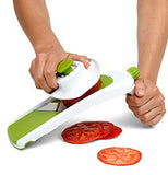 Green and white vegetable slicer in use slicing tomatoes.