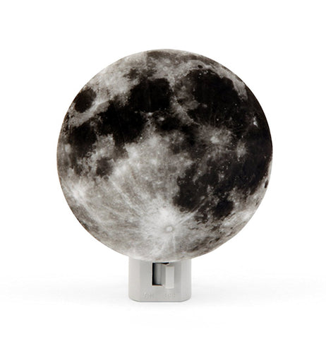 A nightlight in the shape of the moon colored black, gray, and white.