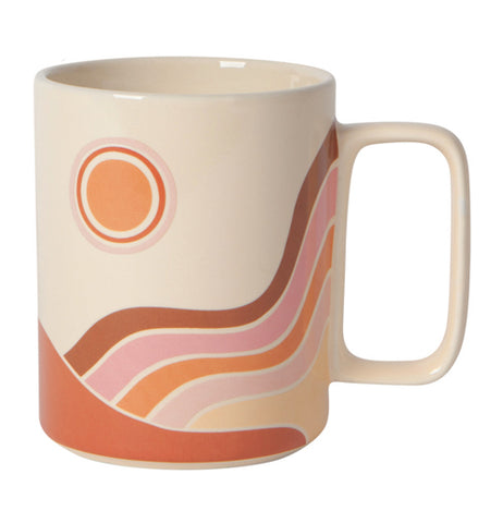 Front view of "Solstice" white ceramic mug with red, orange, and pink sun, rainbow, and sand dune design on a white background.