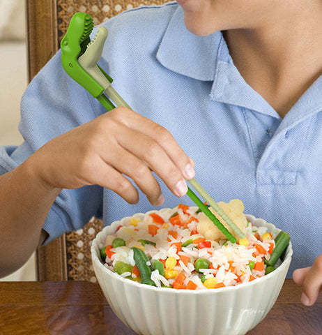 A gentleman using the green T-Rex shaped chopsticks in his dinner bowl  