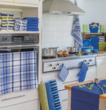 The blue and white striped dish towel is shown hanging from the handle of an oven door in a kitchen.