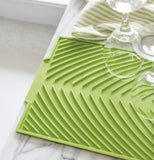 Some wine glasses are shown drying on the green drying mat.