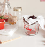 The cheesecloth is shown holding strawberries in a measuring cup.