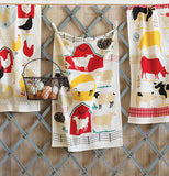 Three dishtowels with simple representations of farm animals, barns, and fences hanging from a rack with a basket of eggs.