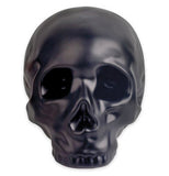 Black stoneware coin bank in the shape of a skull.