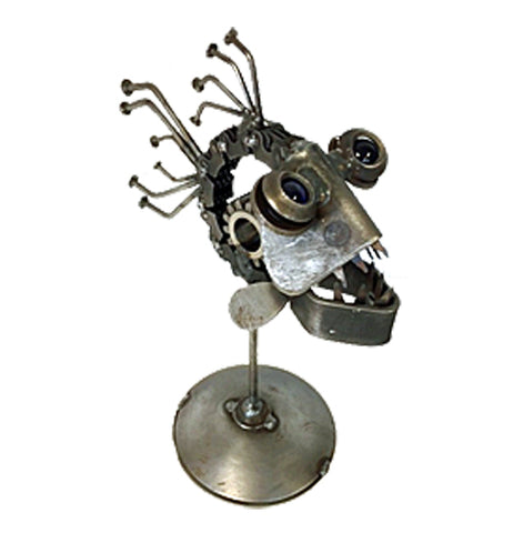 A sculpture of a piranha is made out of recycled metal. It's attached to a small circular platform with a pole. The piranha is facing the right corner.