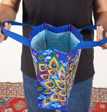 Person holding open a blue handy tote bag with beautiful peacock feather design on the side.