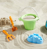 The Sand Play Set has a green bucket, a blue sand castle mold, a brown shovel, and a brown rake on Sand.