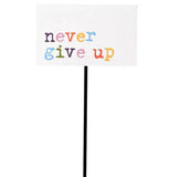 A tiny pot pick with a sign. The sign reads "never give up." The letters are purple, pink, orange, yellow, blue, and green.