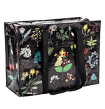 This black bag has an assortment of different plant illustrations covering its front and top cover. A black zipper runs across the top. The plants include green, red, white, and blue leaves. A few yellow flowers cover the top, and some green and white bushes cover the bottom.