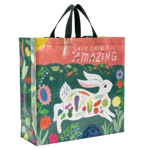 The "Your Garden is Amazing" Shopper Bag has a pink banner on top that says "Your Garden is Amazing" above a white bunny running through a flower garden with vegetables on its body. 