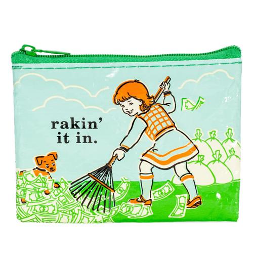 Coin purse with with a green zipper and an image of a girl raking money that her dog is playing in with white bags of cash in the background. It has the words Rakin&