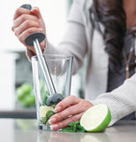 A lady showing how to use the true shaker it is longe metal bar with a handle on one side and a rounded bottom so that you can squeeze your fruit in your glass.