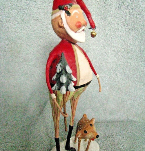 The Santa Claus figurine with the baby Comet reindeer and the small Christmas tree is shown from the side against a blue and white background.