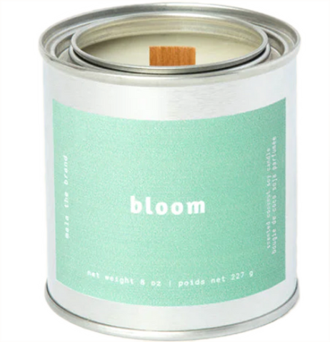 A gray tin candle-shaped can with a pastel green label. The label says "Mala the brand--bloom--Net weight 8 oz. -- scented coconut soy candle." There is also French text, but this alt text writer is woefully monolingual.
