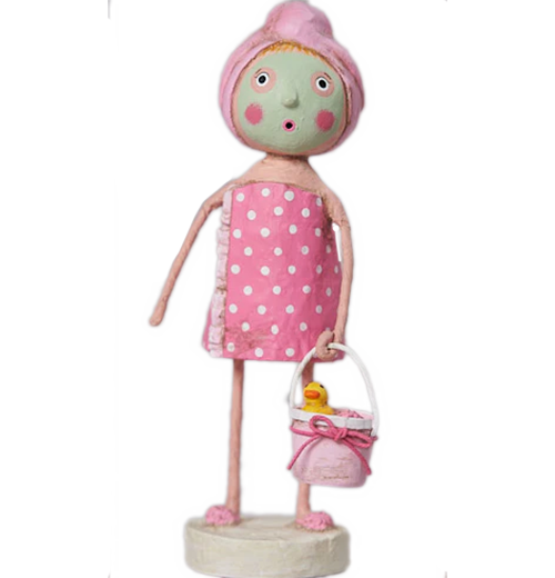A rosy cheeked girl wears a green face mask and pastel pink towel. She is wearing a pink towel around her body, pastel pink slippers, and carries a white and pastel pink with a pink bow around it. The bucket has a yellow rubber ducky with an orange bill.