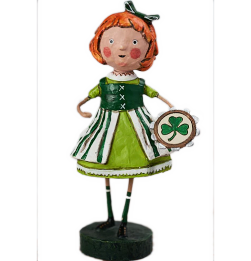 A figurine of a rosy cheeked young girl with a green hair bow. She is wearing a collared green and white dress, and is holding a brown, silver, and beige tambourine with a green three-leafed clover on it.