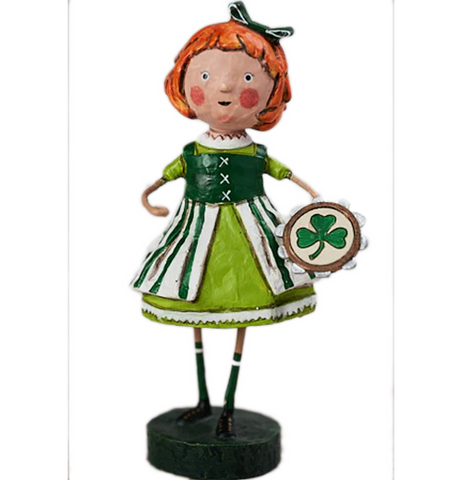 A figurine of a rosy cheeked young girl with a green hair bow. She is wearing a collared green and white dress, and is holding a brown, silver, and beige tambourine with a green three-leafed clover on it.