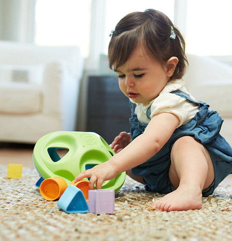 Baby playing with her shape sorter kids game with square, star, circle, and triangle shapes. 