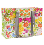 This white tote bag with gray handles is shown with a design of pink, orange, yellow, and periwinkle blue flowers.