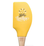 Yellow silicone and tan rubberwood handle spatula with smiling sun that says "Hello Sunshine"