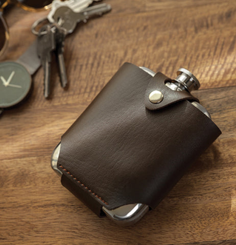 The flask and traveling case sits on the wooden table with the keys. 