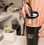 The lid is shown being put on a drinking cup with a black and silver straw being put through it.