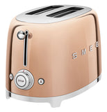 a rose gold colored toaster with 2 slots on top, on the right side of the word SMEG. the front has a slider and bellow it are two buttons, one has a snowflake, the other a heat symbol, between them is a knob that controls the cooking.