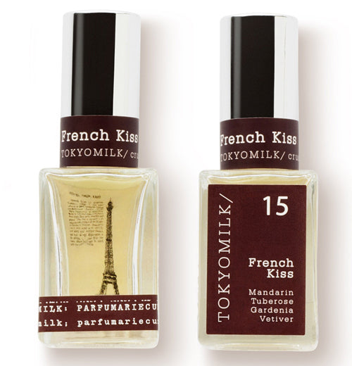 Two French Kiss perfume bottles with square base and chrome lids that contain the words French Kiss and Tokyo Milk. One bottle contains the text that describes the scent of the perfume. Another bottle contains the picture of the Eiffel Tower with words the the left of the building 