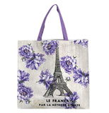 The Small "French Kiss" Tote Bag features black text reading "Le Francais Par La Methode Directe" along with the Eiffel Tower with purple flowers over a light peach background. 
