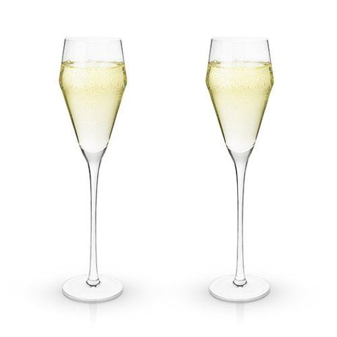 Set of 2 clear crystal "Prosecco" glasses with angled design filled with white wine over a white background.