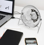 The fan is shown plugged into a laptop computer on a table in front of a smart phone.
