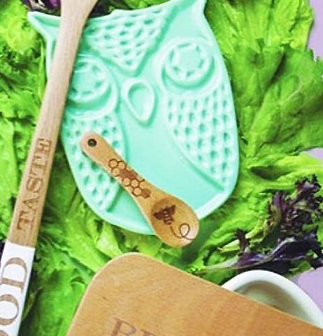 The beechwood spoon is resting on a teal, owl shaped trivet.