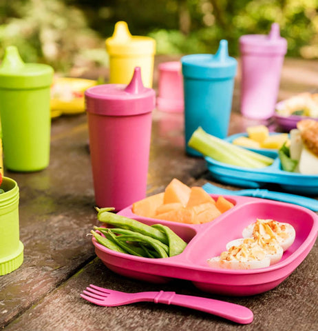 The "Butterfly" Spill Proof Cups sits on the table with a matching divider plate with deviled eggs, snap peas, cut cantaloupe pieces and utensils. 