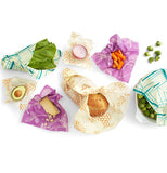 Seven food wraps each laid out with a different vegetable in it. the bread wrap has a loaf of bread in it.