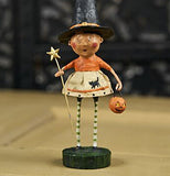 The witch figurine is shown sitting on a wooden table in front of a black wall.