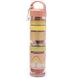 Multiple, plastic stackable snack containers are pastel pink, yellow, green, and transparent in color. A steel carabiner hangs off a small handle. The snack containers are stacked together. There is food in the containers.