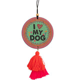 A round multi-color air freshener has the quote "I heart my dog" on it. It has an elastic hanger with a wooden bead on top, and a orange and red yarn tassel hanging off the bottom.