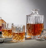 The two crystal glasses sit next to a glass alcohol container on a table.