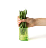 The ends of green beans are being put through the open end of the cylinder.