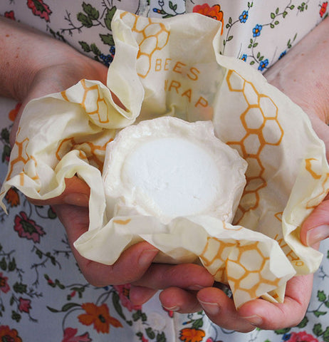 A person holding a single use food wrap in their hands wrapped around food.